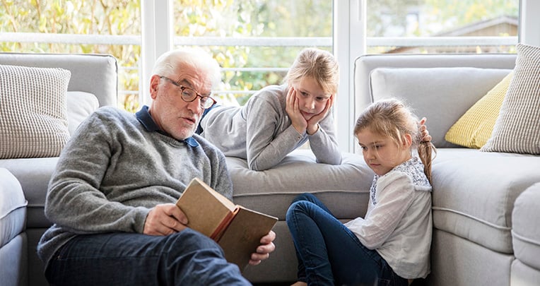 Grandfather reading to two granddaughters
